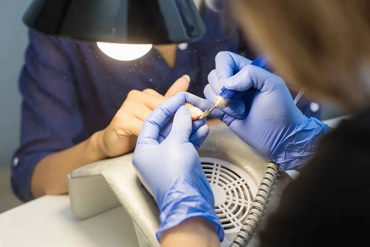 Eine Nageldesignerin entfernt alten Gel-Lack mit einer elektrischen Feile