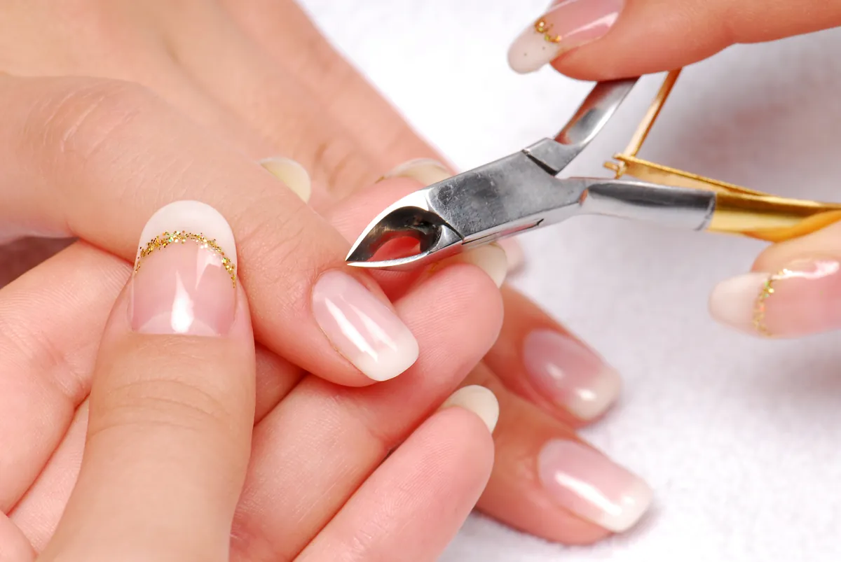 Nagelhautpflege mit einer kleinen Stahlzange am Ansatz des Nagels