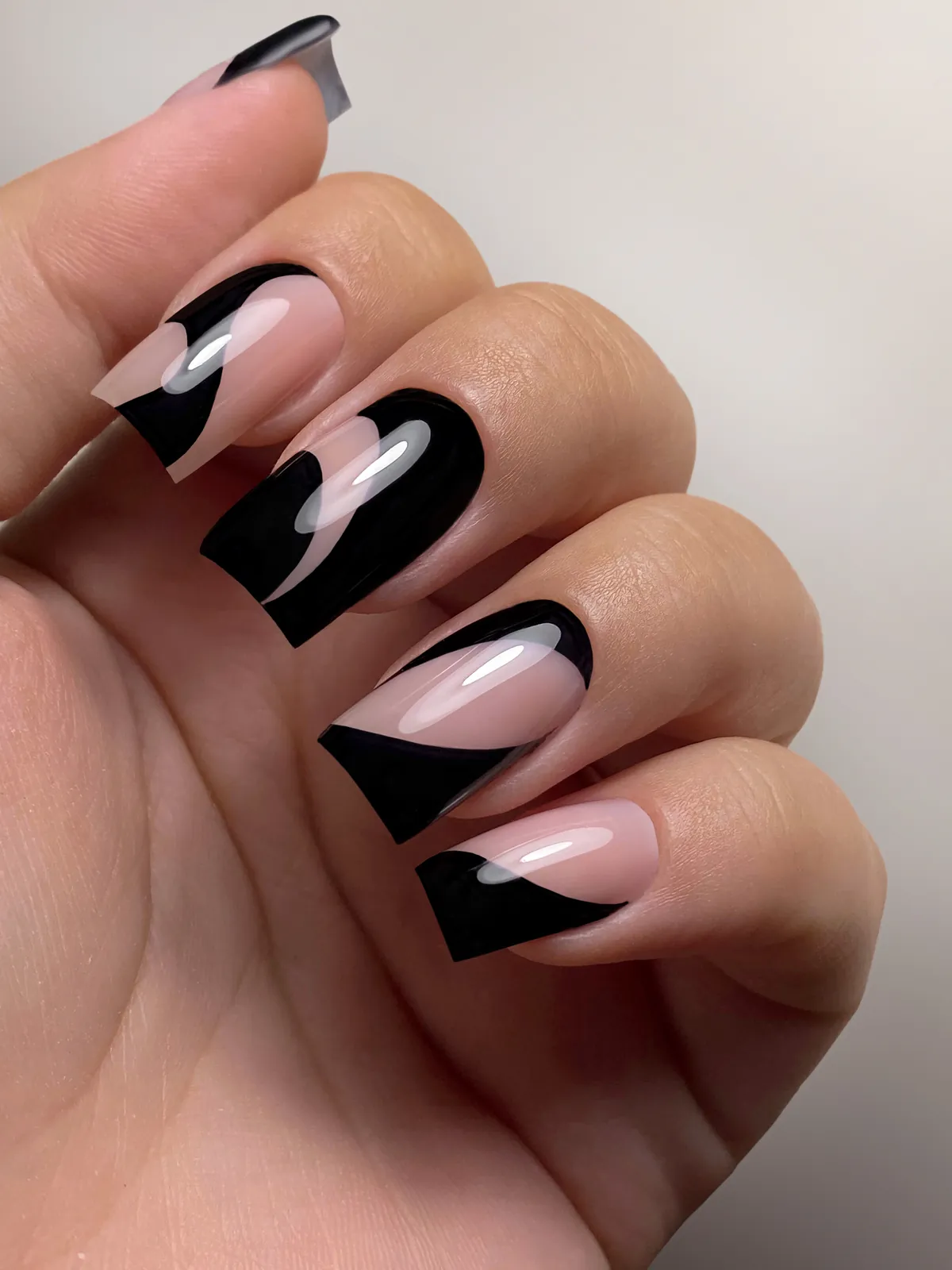 Nudefarbene Nägel mit grafischen schwarzen Spitzen, die einen Teil des Nagels frei lassen